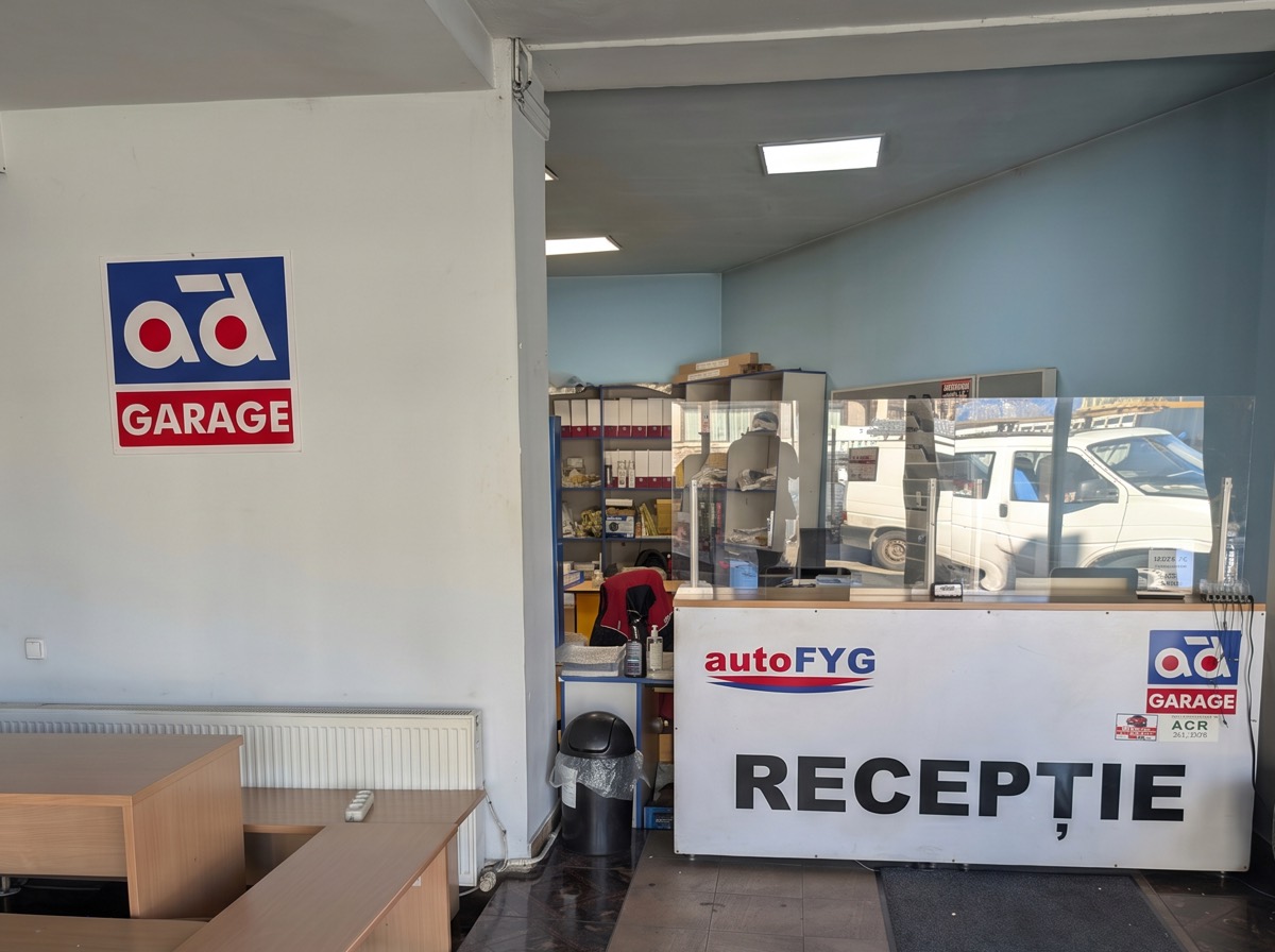 Der Empfang von autoFYG: weiße Theke mit dem autoFYG-Logo und der Aufschrift RECEPȚIE, daneben das Schild von AD Garage